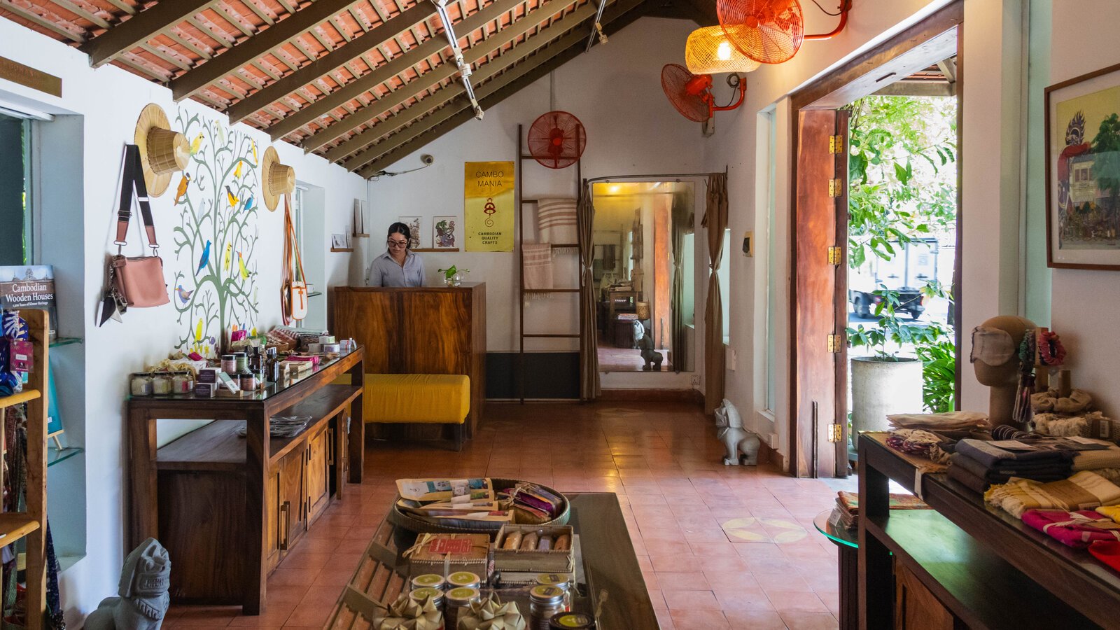 Display tables with artwork, clothing and handcrafted items inside Pavilion Hotel, Cambomania Shop.
