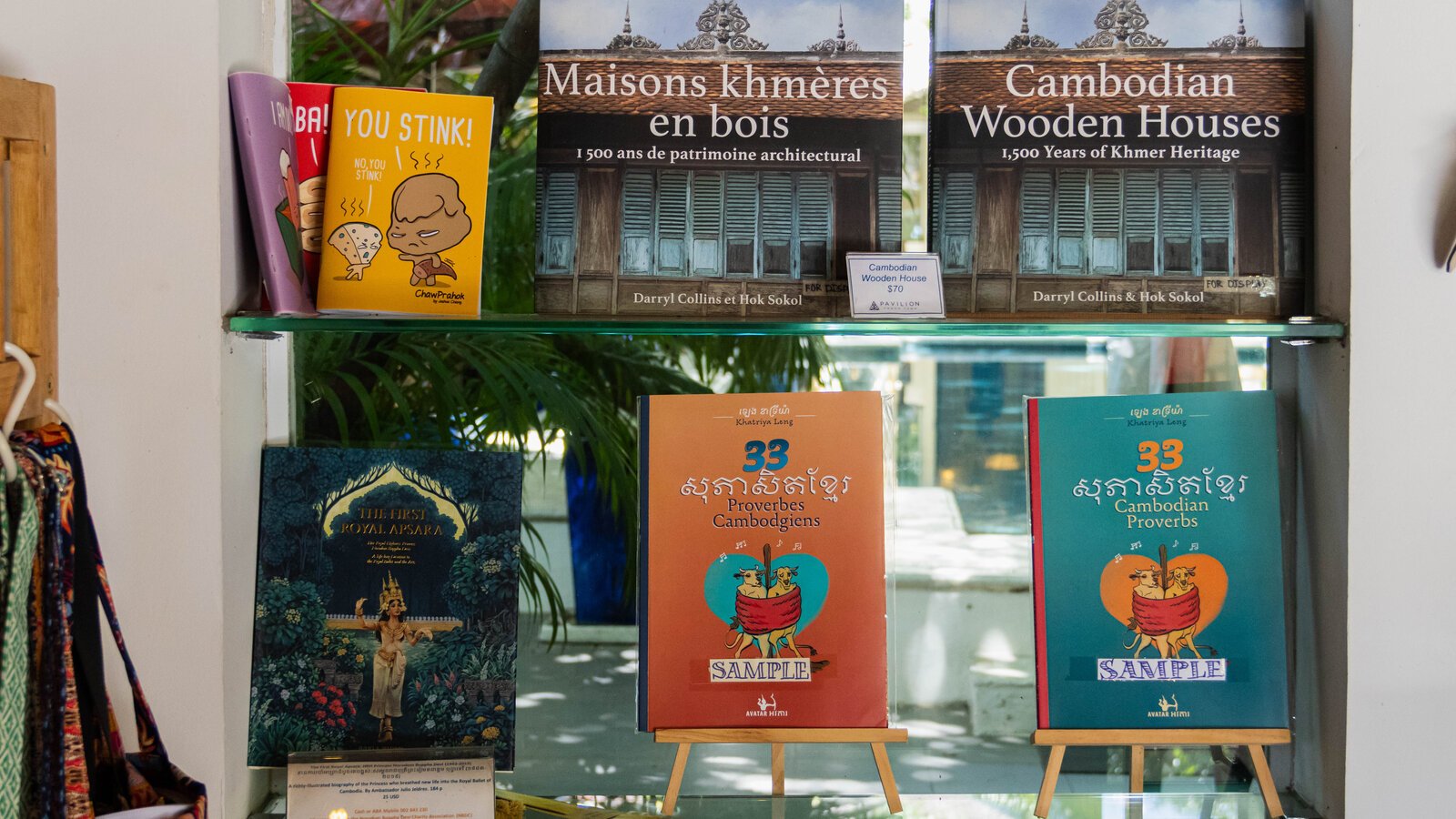 Display shelf featuring books of Cambodian Wooden Houses by Darryl L. Collins & Hok Sokol, and other traditional and local culture books displayed.