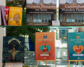 Display shelf featuring books of Cambodian Wooden Houses by Darryl L. Collins & Hok Sokol, and other traditional and local culture books displayed.