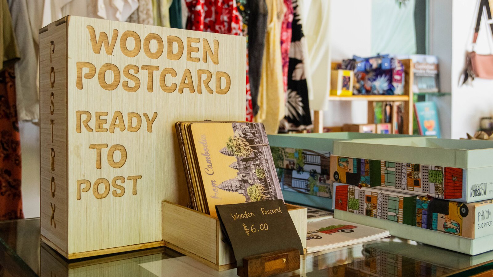 Wooden postcard souvenirs displayed on a glass-topped table among locally inspired gifts.