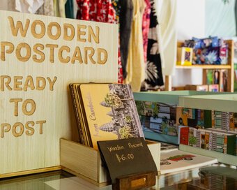 Wooden postcard souvenirs displayed on a glass-topped table among locally inspired gifts.
