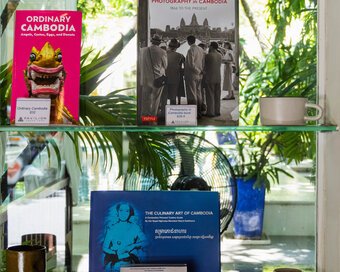Selection of books featuring the Culinary Art of Cambodia by HRH Princess Norodom Rasmi Sobbhana (augmented edition), Photography in Cambodia: 1886 to the Present, by Nicholas Coffill, arranged on a display shelf.