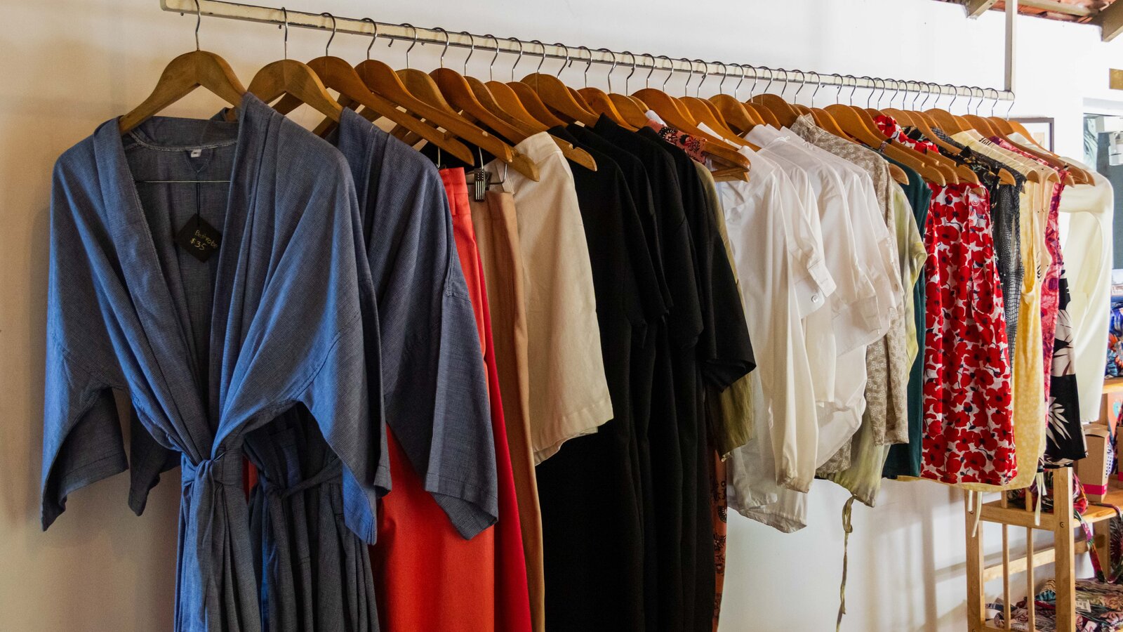 Garments arranged on wooden hangers inside Cambomania shop by Pavilion Hotel.