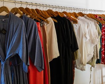 Garments arranged on wooden hangers inside Cambomania shop by Pavilion Hotel.