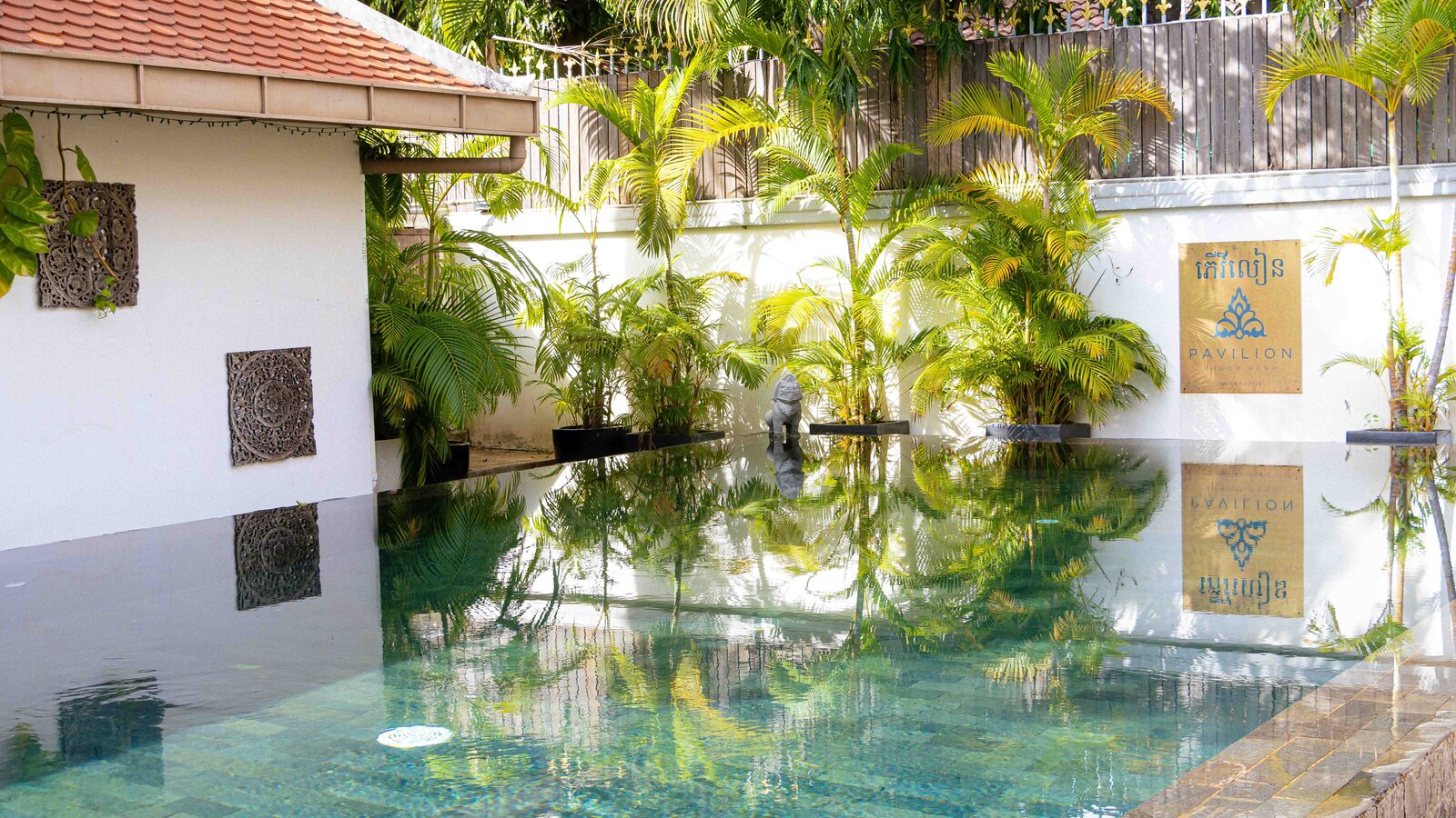Reflections on the sun pool beside the Pavilion sign and planted border.