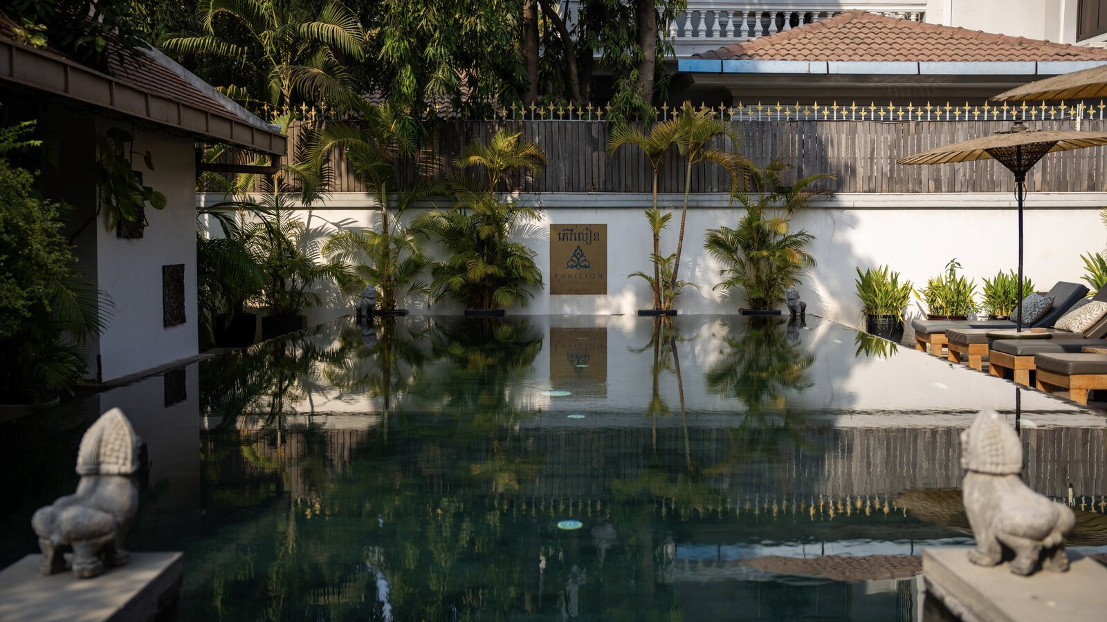 Sun Pool with sun bed loungers and Khmer guardian lions display.