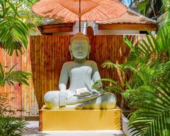 Seated Buddha statue beneath parasol surrounded Pavilion’s garden in Phnom Penh