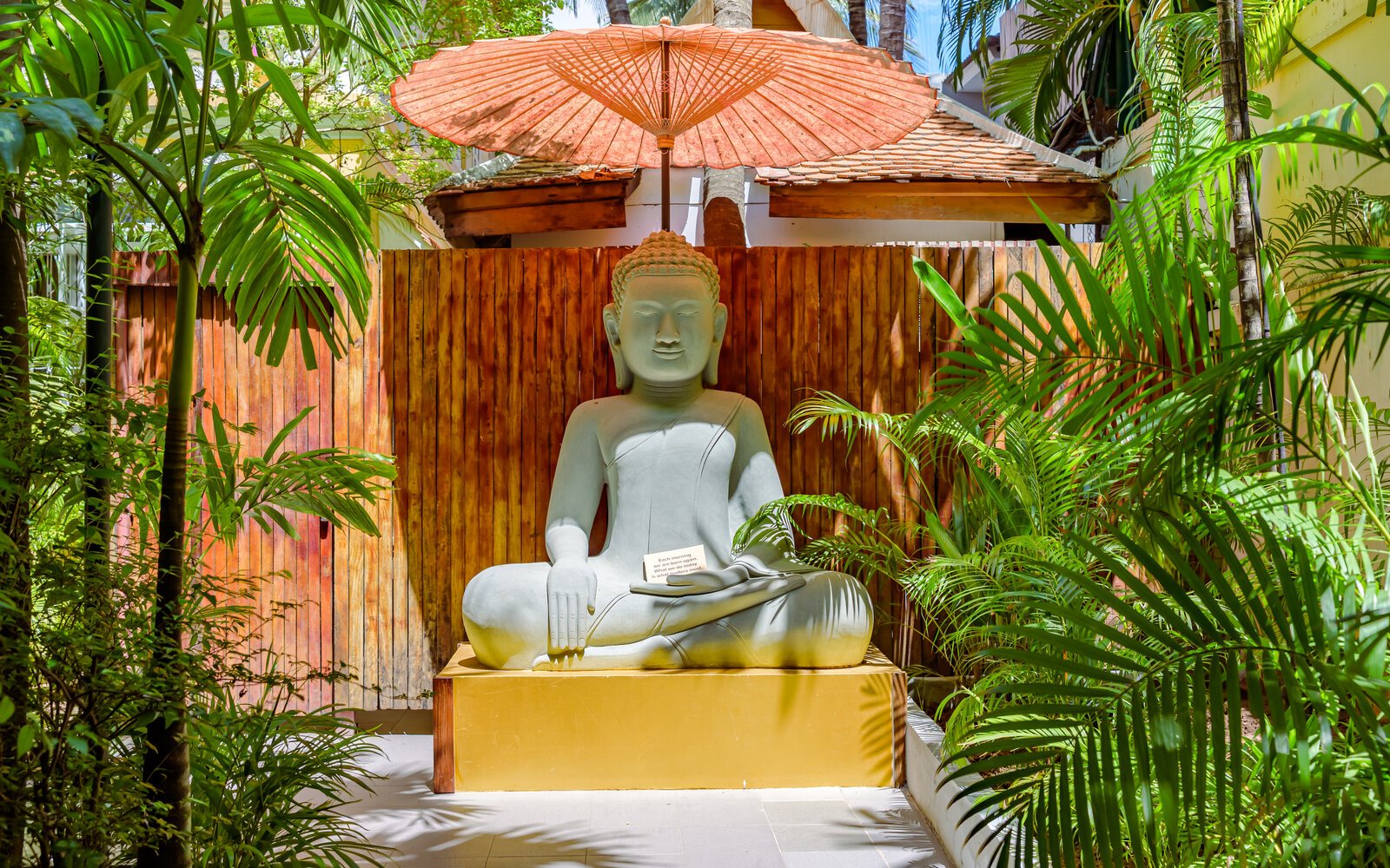 Seated Buddha statue beneath parasol surrounded Pavilion’s garden in Phnom Penh