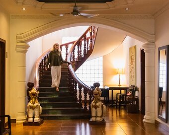 Guest descending the wooden staircase in Pavilion’s heritage lobby, featuring decorative owner's personal collection.