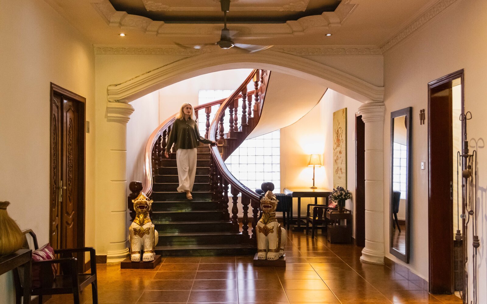 Guest descending the wooden staircase in Pavilion’s heritage lobby, featuring decorative owner's personal collection.