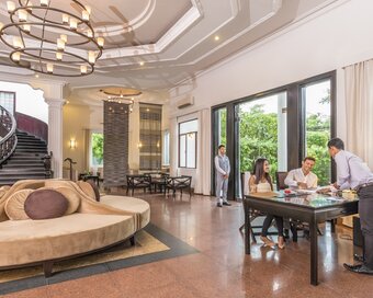 Guests checking in with hotel staff inside the lobby with high ceilings and a grand staircase at White Mansion Hotel, Phnom Penh