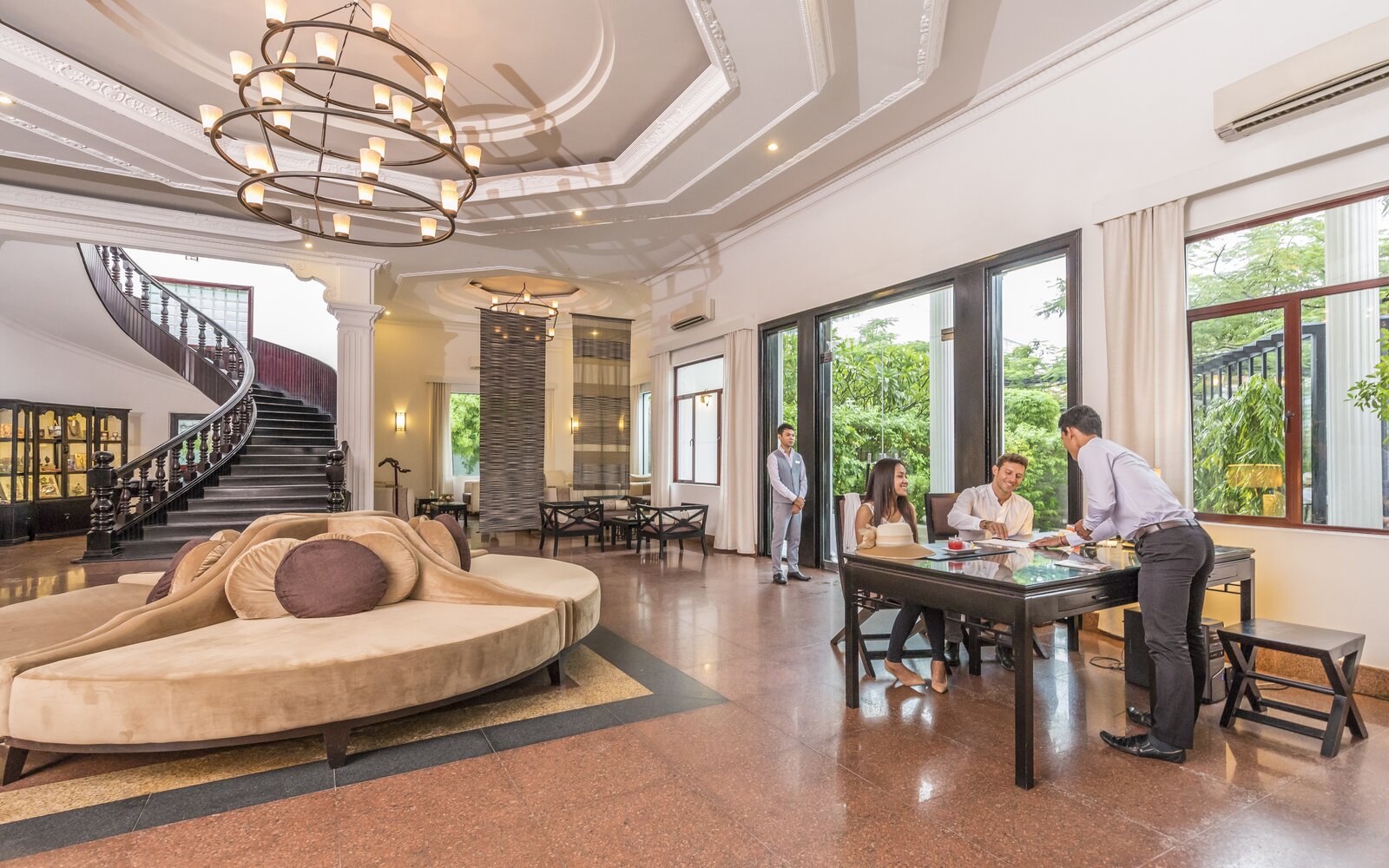 Guests checking in with hotel staff inside the lobby with high ceilings and a grand staircase at White Mansion Hotel, Phnom Penh