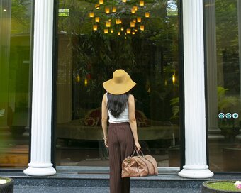 Guest carrying a travel bag walks up the steps toward the hotel's glass doors of White Mansion, Phnom Penh