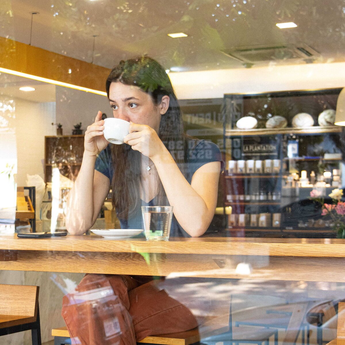Coffee goer sitting at window counter drinking coffee, Le Café at White Mansion Hotel, Phnom Penh.